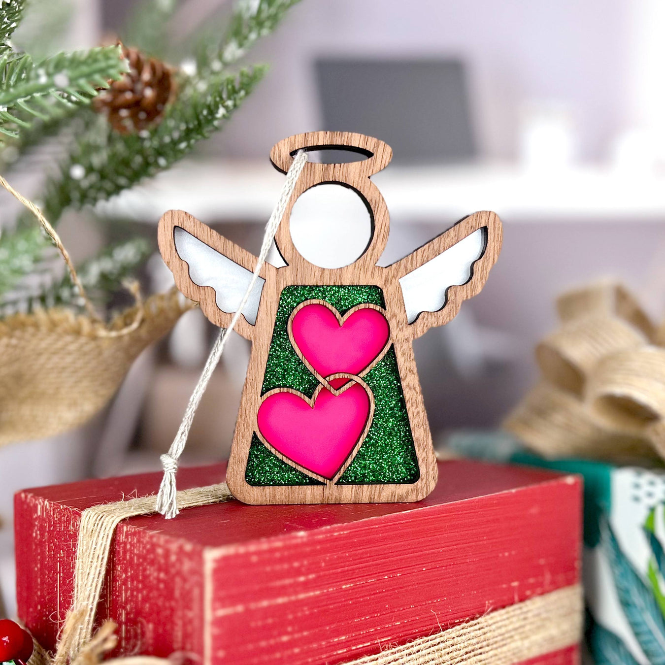 A Forged Flare® Christmas angel ornament with vibrant pink hearts, a charming Christmas present idea among other festive Christmas gifts.