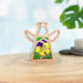 The Pansy Ornament, a 3.5-inch angel figurine from Mother's Angels® by Forged Flare®, beautifully captures a small wooden angel with outstretched wings and a halo. Featuring an intricate floral design adorned with purple and yellow flowers, this charming piece stands elegantly on a wooden surface against a softly blurred backdrop that includes lush greenery, making it an enchanting addition to any floral decor.