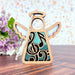 The Music Ornament from Forged Flare® is a 3.5" Angel Figurine from the Mother's Angels® collection, featuring intricate black musical notes on its wooden body. It comes complete with a halo, wings, and a white string loop for hanging. The backdrop includes a rustic wooden surface and purple flowers with green leaves on the left side—making it an ideal gift for music teachers.