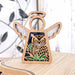 The Owl Ornament | 3.5" Angel Figurine from Mother's Angels® by Forged Flare® features a wooden angel-shaped design with intricate cutouts showcasing an owl among green leaves. This ornament displays white wings, a halo, and includes a string for hanging. Perfect as a memorial or bird lover's gift, it is displayed on a light wooden surface with blurred decor in the background.