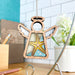 The Starfish Ornament | 3.5" Angel Figurine by Forged Flare® hangs from a string, featuring white painted wings and vibrant teal and yellow details that make it ideal for beach house decor. Displayed against a modern tiled background with a potted plant and pencil holder nearby, this charming piece from the Mother's Angels® collection adds a touch of coastal elegance to any setting.