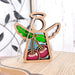 The Forged Flare® Sweet Cherries Ornament | 3.5" Angel Figurine from the Mother's Angels® collection showcases a wooden angel with hollow wings and head, adorned with stained glass–style cherries. The body features a depiction of two charming cherries accompanied by green leaves. Placed on a light-colored wooden surface, the Christmas tree ornament has a blurred bird decoration in the background.