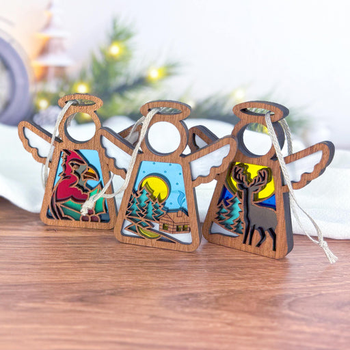 A set of three angel ornaments from the Mother's Angels® collection by Forged Flare® showcases dazzling stained glass-style inserts, elegantly adorning any wooden surface. Each 3.5" figurine in the Winter Angels 3-Piece Bundle—Warm Welcome, Winter Cardinal, and Winter Deer—features enchanting winter scenes: a cardinal, a snow-kissed cabin with pine trees, and a deer in the forest. These pieces are perfect for adding holiday charm to your festive decor.