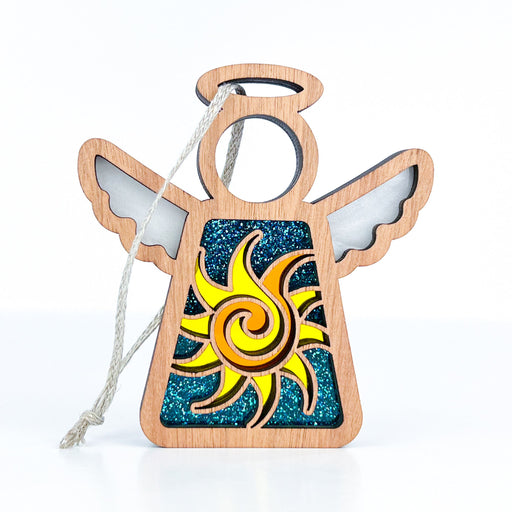 The Celestial Sun Ornament by Forged Flare® is a 3.5" angel figurine, part of the Mother's Angels® collection. This wooden ornament features cutout wings, a circular halo, and a body adorned with a yellow and orange spiral design set against a glittery blue background. Perfect for hanging with its attached string, this simple yet stylized Christmas ornament makes for a charming beach gift.