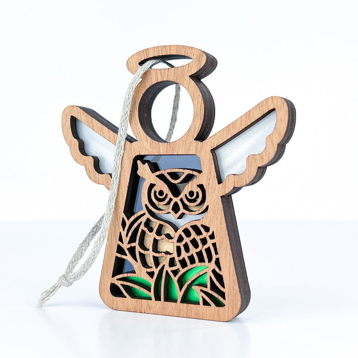 The Owl Ornament by Forged Flare® is a 3.5" angel-shaped figurine from the Mother's Angels® collection, featuring an intricate owl design. This bird lover's gift has a light wood finish and is hung by a braided linen string, complete with small wings and a halo.