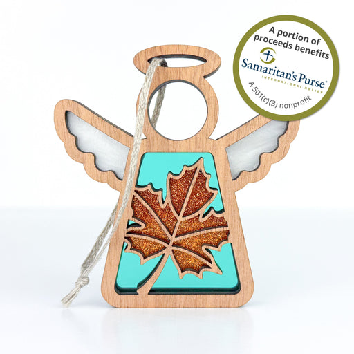 Discover the Sugar Maple Leaf for Charity Ornament, a 3.5-inch angel figurine from Forged Flare's Mother's Angels® collection. This charming piece features a wooden frame and a transparent turquoise body adorned with a glittery orange maple leaf design. A twine loop allows for easy hanging, adding both charm and elegance to any space.