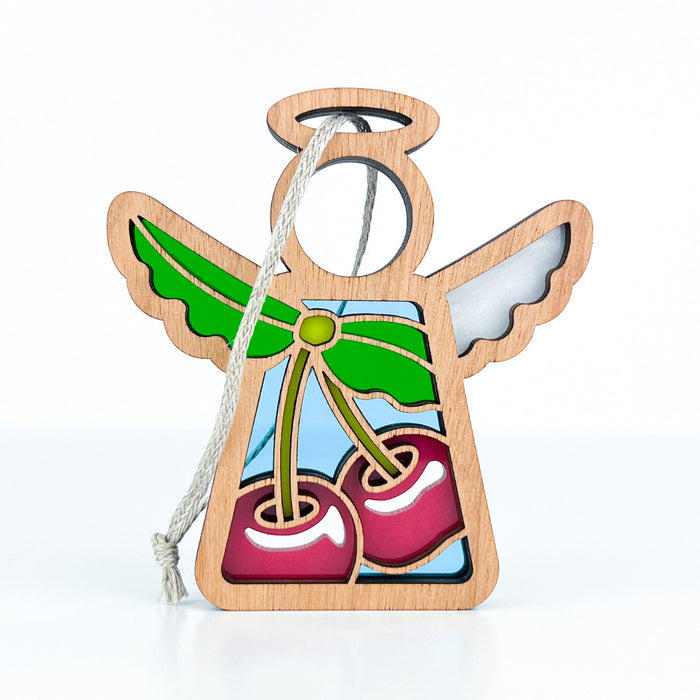 The Sweet Cherries Ornament, a 3.5" Angel Figurine from Mother's Angels® by Forged Flare®, features a wooden angel with a cutout halo and wings, and a body adorned with a colorful stained glass–style design of sweet cherries on green stems. It includes a braided linen string for easy hanging. Ideal as an angel figurine or Christmas tree ornament, this beautiful piece is displayed against a plain white background.