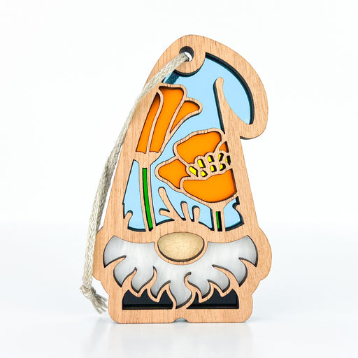 The California Poppy Ornament from Forged Flare®, measuring 3.75 inches, features a charming garden gnome with an orange flower design, a white beard, and a tall hat set against a blue background. A string is threaded through a hole near the top for easy hanging. As part of the Nature’s Gnomes™ collection, it's perfect for use as a gnome Christmas ornament.