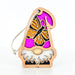 The Monarch Butterfly Ornament from the Nature's Gnomes™ collection by Forged Flare® features a wooden gnome with a cutout design adorned with a vibrant pink Monarch butterfly on its hat. The gnome has a white beard and a small nose peeking out, and comes with a natural twine loop for hanging. This 3.75" garden gnome ornament is perfect for enhancing any outdoor space.